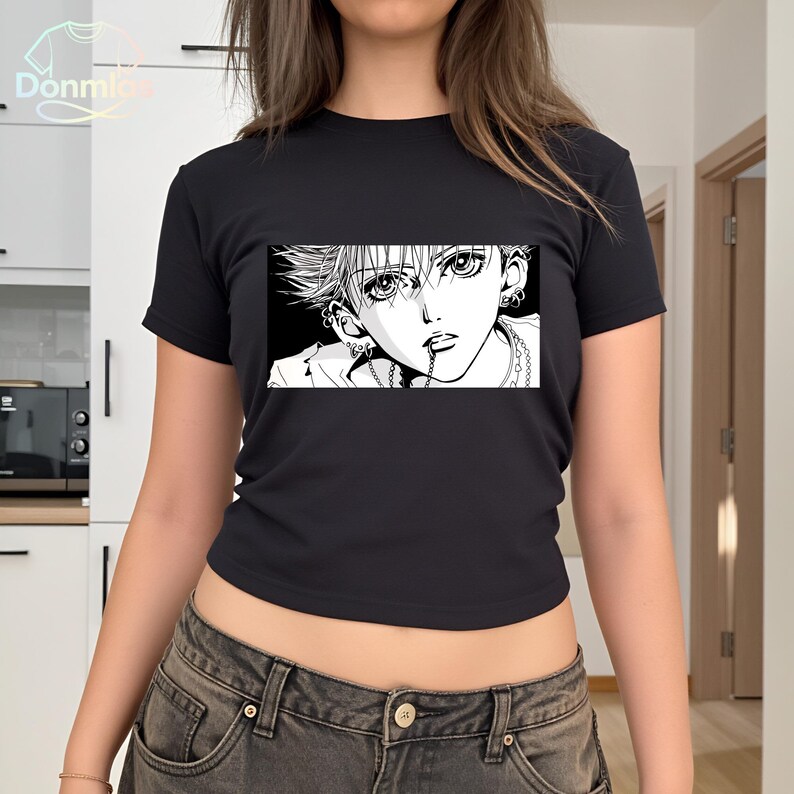 May include: Black crop top featuring a black and white manga illustration. The graphic depicts a person with spiky hair, multiple piercings, and a chain necklace. The top has a crew neck and short sleeves.