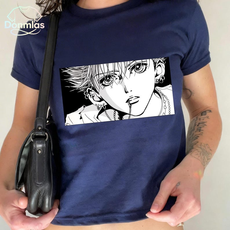 May include: Navy blue t-shirt featuring a black and white manga-style illustration of a person's face. The graphic is rectangular and centered on the shirt. The shirt has short sleeves and a crew neck.