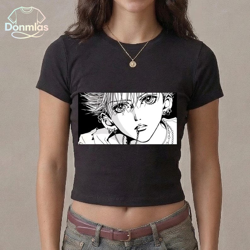 May include: Black crop top featuring a manga-style graphic of a person with spiky hair, multiple earrings, and a chain in their mouth. The graphic is in black and white. The shirt has a crew neck and short sleeves.