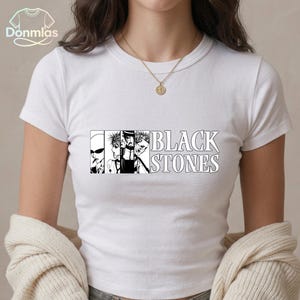May include: White t-shirt featuring a black and white graphic of a band with the text "BLACK STONES". The design includes stylized illustrations of band members. A casual, everyday wear tee.