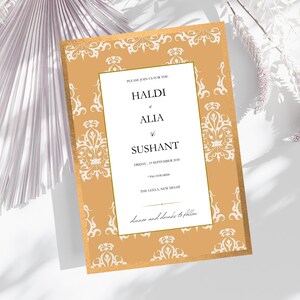 Puede incluir: Una invitación de boda con borde dorado y diseño floral blanco ornamentado. La invitación incluye los nombres Haldi, Alia y Sushant, junto con la fecha y la hora. También se incluye el texto "Cena y bebidas a continuación".