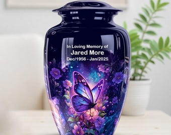May include: A navy blue cremation urn with a butterfly and floral design. The urn has a glossy finish and features the text "In Loving Memory of Jared More Dec/1956 - Jan/2025". The butterfly is purple and blue.