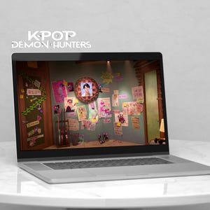 Puede incluir: Un portátil plateado muestra una colorida escena interior con carteles y una foto enmarcada. La pantalla muestra el texto "KPOP DEMON HUNTERS" encima del portátil. El portátil está sobre una mesa redonda blanca.
