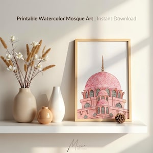 May include: Printable watercolor mosque art in a wooden frame. The artwork features a pink mosque with a dome and minaret. The image is displayed on a white shelf with vases and decorative elements. Text on the image reads: Printable Watercolor Mosque Art | Instant Download.
