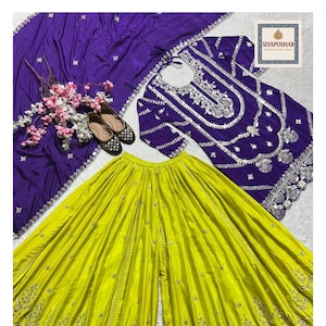 May include: A vibrant ensemble featuring a lime green palazzo pant set, a purple embroidered top, and a matching scarf. The outfit includes a pair of black and tan flats and is accented with floral decorations. The brand name "Siyaposhak" is visible.