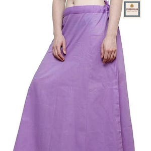 May include: A lavender-colored, full-length petticoat. The garment is made of a smooth fabric and features a tie closure at the waist. The brand name "Siyaposhak" is visible in the upper right corner and at the bottom of the petticoat.