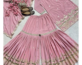 Op de afbeelding: Een lichtroze salwar kameez-set met gouden borduursels. De set bestaat uit een tuniek, een broek met wijde pijpen en een bijpassende sjaal. Gouden borduursels en versieringen sieren de randen en details van de outfit. De merknaam "Siyaposhak" is zichtbaar.