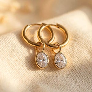 Ovala örhängen i guld | Huggie Hoops med simulerade diamanter | Vattentäta örhängen i rostfritt stål för vardagsbruk | Ovala Huggies i guld med CZ-kristaller