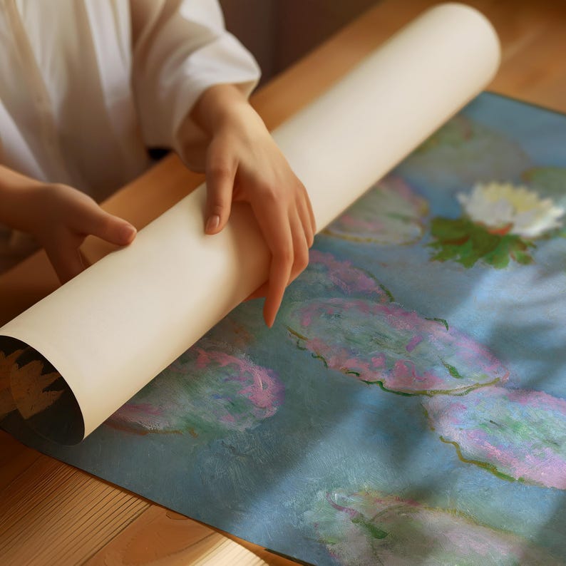 May include: A rolled-up, off-white art print is held by a person. The print reveals a colorful painting of water lilies in shades of blue, pink, and green. The artwork is displayed on a wooden surface.