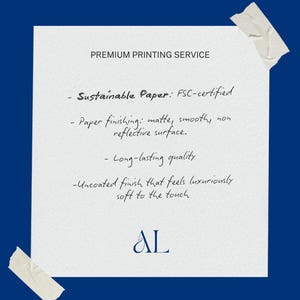 May include: A white paper with text about premium printing services, including sustainable paper, matte finish, and long-lasting quality. The paper is taped to a dark blue background. The text includes the initials "AL".