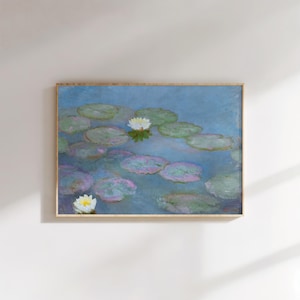 May include: A framed print of a water lily pond. The painting features lily pads in shades of green and purple floating on a blue water surface. White water lilies are scattered throughout the scene. The frame is a light brown color.
