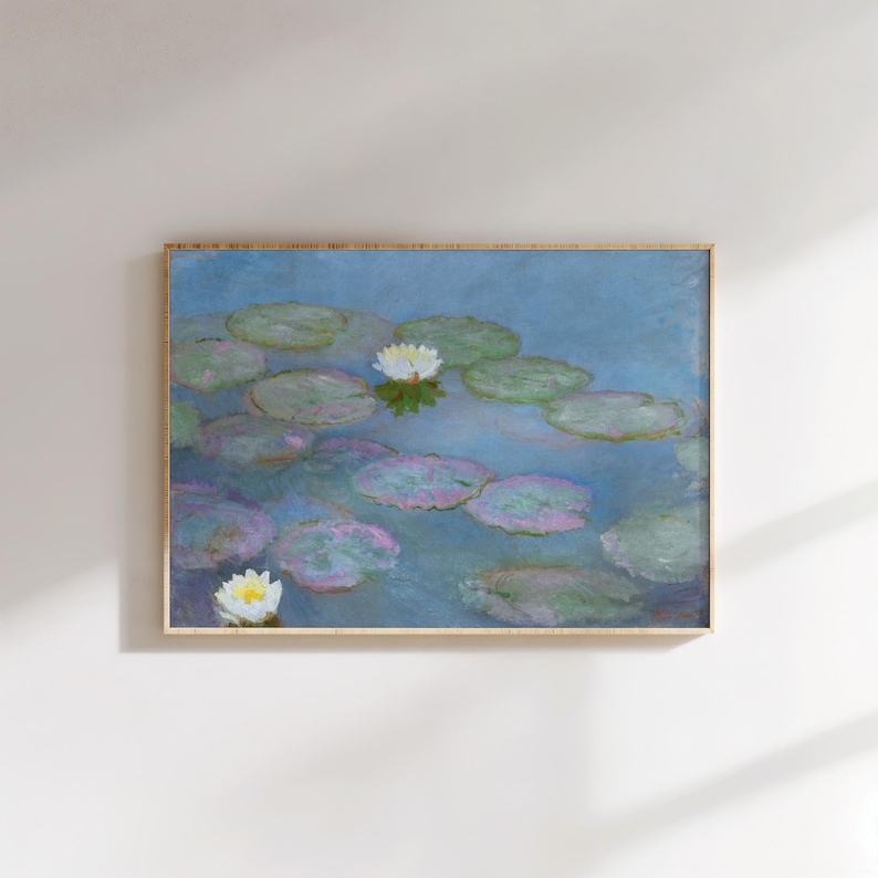 May include: A framed print of a water lily pond. The painting features lily pads in shades of green and purple floating on a blue water surface. White water lilies are scattered throughout the scene. The frame is a light brown color.