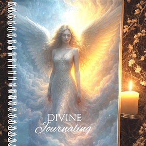 Puede incluir: Un diario con espiral con una ilustración celestial. La portada presenta a una mujer con alas de ángel, sobre un fondo de nubes y luz dorada. Las palabras "DIVINE Journaling" están escritas en la portada.