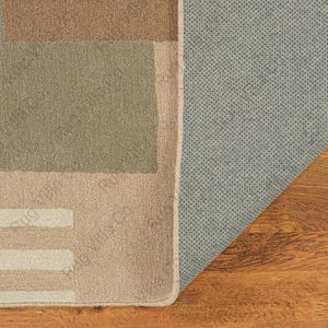 K&ouml;nnte beinhalten: Ein rechteckiger Teppich mit einem geometrischen Muster in Braun-, Beige- und Gr&uuml;nt&ouml;nen. Die Unterseite des Teppichs ist hellgrau mit einer gepunkteten Textur. Der Teppich ist teilweise aufgerollt und gibt den Blick auf den Holzboden frei.