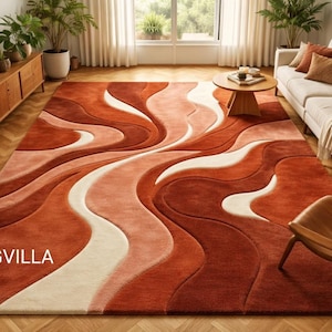 May include: A large, abstract rug with a flowing, wave-like design in shades of rust, peach, and cream. The rug features the text "RUGVILLA" in white. The rug is placed in a living room setting with a sofa, chair, and wooden furniture.