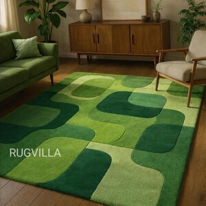 May include: A green area rug with a geometric pattern of overlapping shapes in various shades of green. The rug is rectangular and covers a large portion of the wooden floor. The text "RUGVILLA" is visible on the rug.