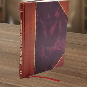 Op de afbeelding: Een hardcover boek met een bordeauxrode leren kaft en een dieppaars middenpaneel. De rug en hoeken van het boek zijn geaccentueerd met gouden randen. De titel "Ames Compendium of Practical and Ornamental Penmanship" staat op de rug. Een rood lint als boekenlegger steekt uit het boek.