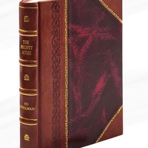 May include: A hardcover book titled "The Mighty Atom" by Ed Spielman. The book has a burgundy leather cover with gold accents and a decorative spine. A red ribbon bookmark is visible.