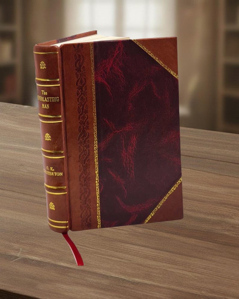 May include: A hardcover book titled "The Everlasting Man" by G.K. Chesterton. The book has a brown leather cover with gold accents and a red bookmark. The cover features a burgundy textured panel.