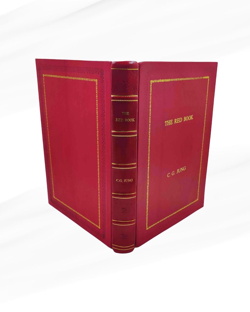 Może przedstawiać: Twarda oprawa książki zatytułowana "The Red Book" autorstwa C.G. Junga. Książka ma żywą czerwoną okładkę ze złotymi literami i detalami. Grzbiet jest r&oacute;wnież czerwony ze złotymi akcentami. Książka jest otwarta.