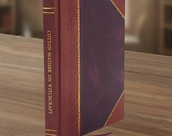 Op de afbeelding: Een hardcover boek getiteld "Cotton Mather on Witchcraft" met een bordeauxrode leren kaft en gouden accenten. Het boek heeft een decoratieve rug en een donkerpaars middenpaneel. Een rood lint als boekenlegger is zichtbaar.