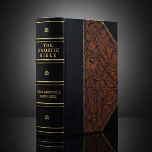May include: A hardback book titled "The Gnostic Bible" by Willis Barnstone & Marvin Meyer. The book has a black cover with gold lettering and accents. The right side of the book has a brown, textured cover.