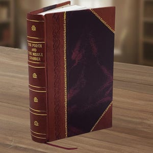 May include: A hardback book titled "The Porch and the Middle Chamber" with a burgundy leather cover. The spine features gold embossed details and a burgundy ribbon bookmark. The cover has a dark burgundy leather section with gold trim.