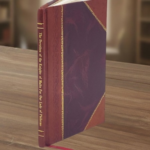 May include: A hardcover book with a burgundy cover and a purple center panel, accented with gold trim. The title "The Devotion of the Knights of Malta For Our Lady of Philermo" is printed in gold on the spine. A red ribbon bookmark is visible.