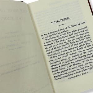 May include: Open book with text on cream-colored pages. The text reads "INTRODUCTION" at the top, followed by paragraphs discussing the Epistle of Jude and the Book of Enoch. The book has a brown cover.