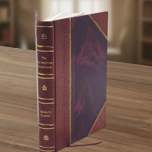 May include: A hardcover book titled The Pythagorean Proposition by Elisha S. Loomis, featuring a deep burgundy leather-like cover with gold foil accents, decorative spine bands, and a marbled pattern on the front panel with a thin ribbon bookmark.