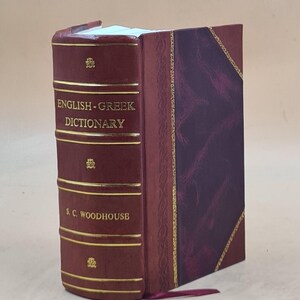 Op de afbeelding: Een Engels-Grieks woordenboek met harde kaft van S. C. Woodhouse met een donkerrode rug voorzien van gouden letters en horizontale banden. De kaft heeft een donkerpaarse gemarmerde textuur met gouden decoratieve randen en een rood leeslint.