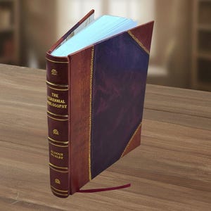 May include: A hardback book titled "The Perennial Philosophy" by Aldous Huxley. The book features a burgundy leather cover with a purple panel and gold detailing. The pages are light blue, and a burgundy ribbon bookmark is present.