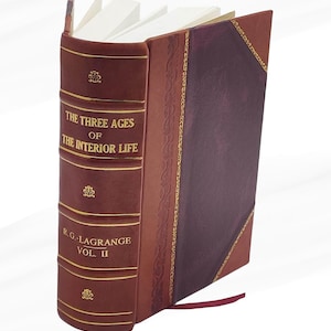 May include: A hardcover book titled "THE THREE AGES OF THE INTERIOR LIFE" by R.G. Lagrange, Vol. II. The book has a burgundy leather cover with gold accents and a maroon spine. The pages are white, and a red ribbon bookmark is visible.