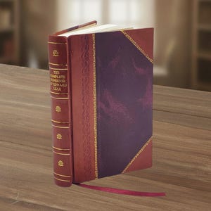 May include: A hardcover book titled "The Complete Nonsense of Edward Lear" stands upright on a wooden surface. The book features a burgundy leather spine with gold accents and a deep purple cover with gold trim. A burgundy ribbon bookmark extends from the pages.