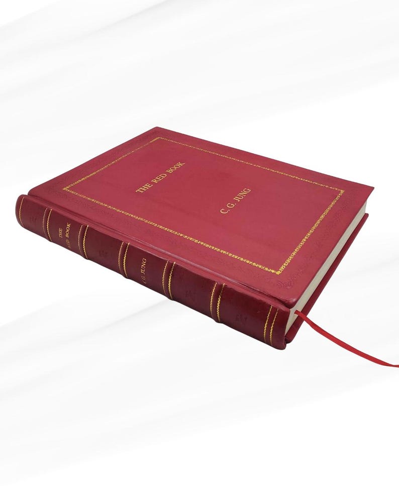 Może przedstawiać: Czerwona książka w twardej oprawie zatytułowana "THE RED BOOK" autorstwa C.G. Junga. Książka ma złote litery i złotą obw&oacute;dkę. Czerwona wstążka służy jako zakładka.