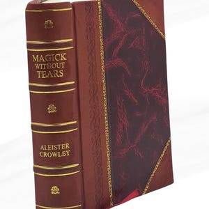 May include: A hardcover book titled "Magick Without Tears" by Aleister Crowley. The book has a dark red leather cover with gold accents and decorative patterns. The cover features a burgundy panel with a textured pattern.