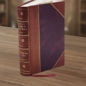 May include: A hardcover book titled "SATAN, PRINCE OF THIS WORLD" by William Guy Carr. The book has a burgundy leather cover with gold accents and a purple panel. A red ribbon bookmark is visible.