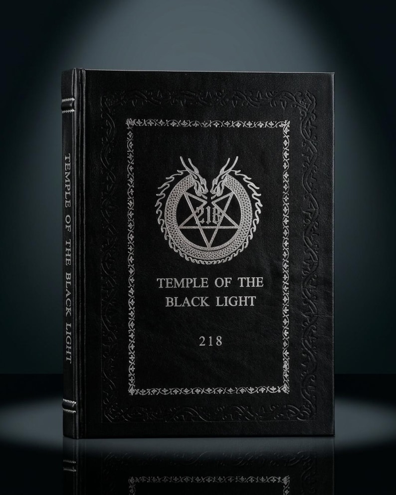 K&ouml;nnte beinhalten: Ein schwarzes Buch mit dem Titel "Temple of the Black Light" in silberner Pr&auml;gung und dekorativen silbernen Bord&uuml;ren. Das Cover zeigt ein Pentagramm in einem Kreis, flankiert von drachenartigen Figuren. Die Nummer "218" steht unter dem Titel.