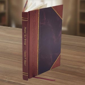Può includere: Un libro con copertina rigida con dorso e copertina bordeaux, con il testo "Master Key System" e "Charles F. Haanel". Il libro ha una copertina viola scuro con finiture dorate e un segnalibro bordeaux. Le pagine sono bianche.