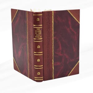 May include: A burgundy leather-bound book titled "The Gospel of the Holy Twelve". The spine features gold lettering and decorative gold detailing. The book is open, displaying the pages. The cover has a textured appearance.