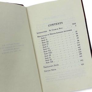 May include: An open book with a brown cover, displaying the contents page. The text includes "CONTENTS," "INTRODUCTION," and "MEDITATIONS OF MARCUS AURELIUS ANTONINUS." Page numbers are listed next to each chapter. The pages are off-white.