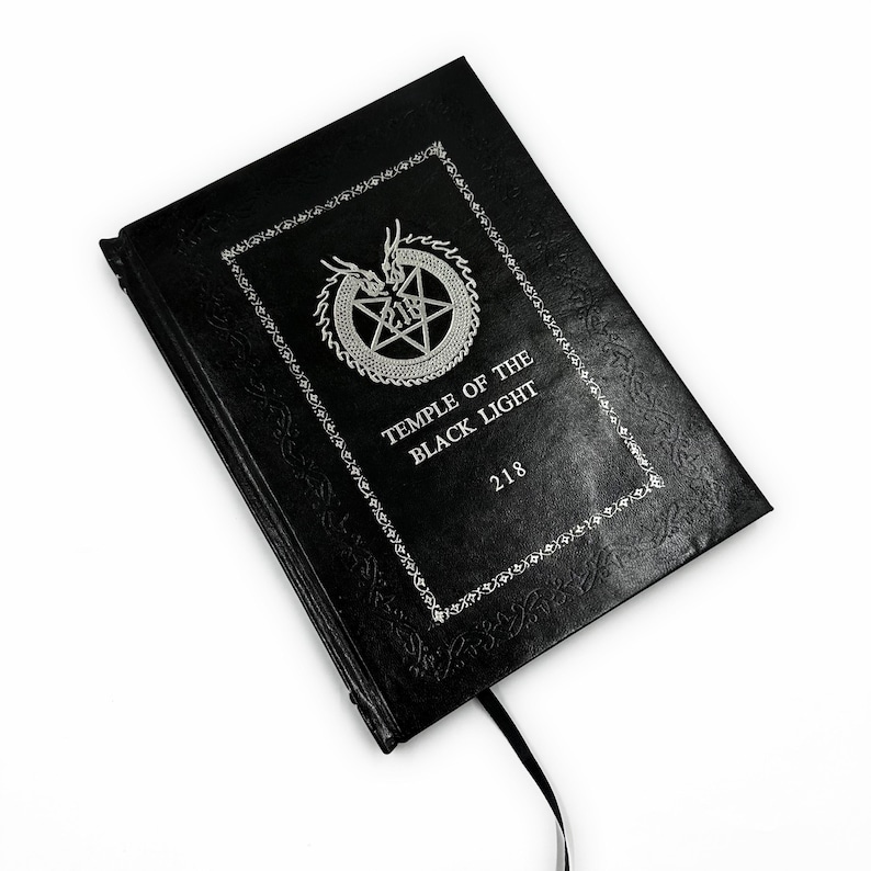 K&ouml;nnte beinhalten: Schwarzes Buch mit gepr&auml;gtem Einband und silbernem Text. Das Cover zeigt einen dekorativen Rand, ein Pentagramm und den Text "TEMPLE OF THE BLACK LIGHT" und "218". Ein schwarzes Leseband ist angebracht.