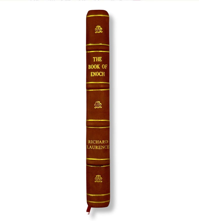May include: A brown hardcover book titled "The Book of Enoch" with gold lettering and accents. The spine features the author's name, Richard Laurence, and decorative gold embellishments. A red ribbon bookmark is visible.