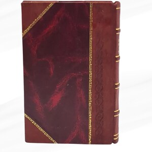 May include: A rectangular book with a burgundy leather cover. The cover has a textured, dark red panel framed by gold trim. The spine is a lighter brown with gold accents, suggesting an antique or classic design.