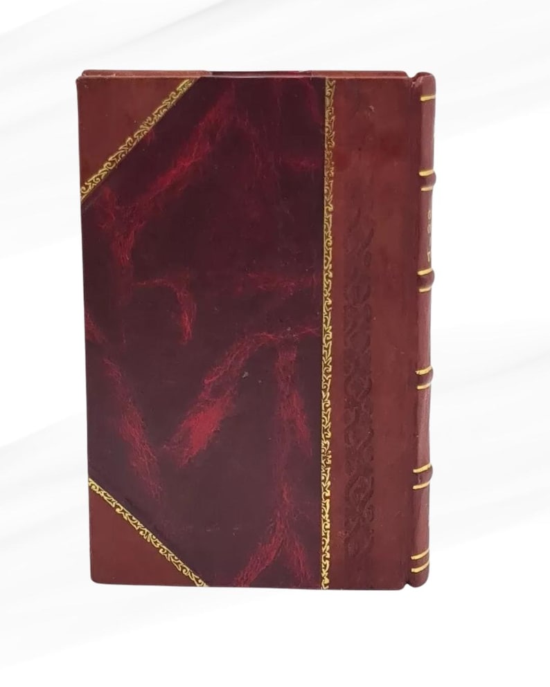 May include: A rectangular book with a burgundy leather cover. The cover has a textured, dark red panel framed by gold trim. The spine is a lighter brown with gold accents, suggesting an antique or classic design.