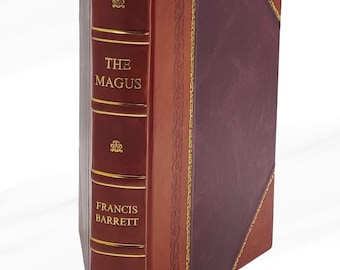May include: A hardcover book titled "The Magus" by Francis Barrett. The book has a burgundy spine with gold lettering and decorative accents. The cover is a combination of burgundy and brown leather with gold trim and a red ribbon bookmark.