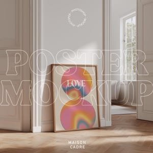 Könnte beinhalten: Ein gerahmtes Poster mit Holzrahmen lehnt an einer Wand. Das Poster zeigt zwei sich überlappende Kreise mit einem Farbverlauf aus Rosa, Orange und Blau. Das Wort "LOVE" ist auf dem oberen Kreis zentriert.