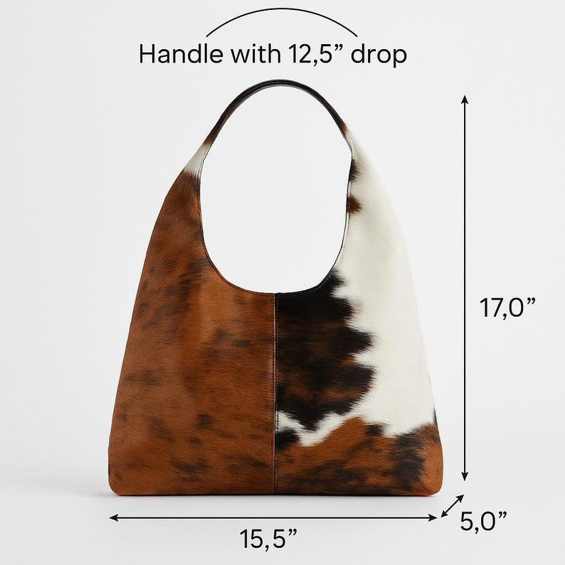 May include: A large cowhide shoulder bag with a handle drop of 31.75 cm. The bag is 43.18 cm tall, 39.37 cm wide, and 12.7 cm deep. The bag features a pattern of brown, black, and white.