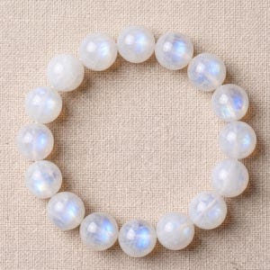 May include: A bracelet made of white moonstone beads. The spherical beads display a milky white hue with iridescent blue and purple flashes. The bracelet is elasticated, and the beads are approximately 1 cm in diameter.