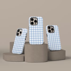 Op de afbeelding: Drie telefoonhoesjes met een lichtblauw en wit ruitpatroon. De hoesjes worden gepresenteerd op een geometrische sokkel in neutrale kleuren. De hoesjes hebben een glanzende afwerking en zijn ontworpen voor een smartphone.